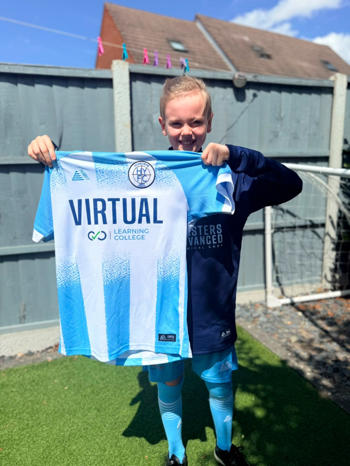 Harborne Youth Football Club player holding a team shirt sponsored by Virtual Learning College